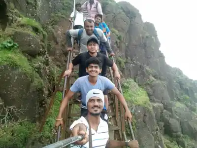 Tour Group climbing steel ladders on rocky cliffs of Kalsubai Trek