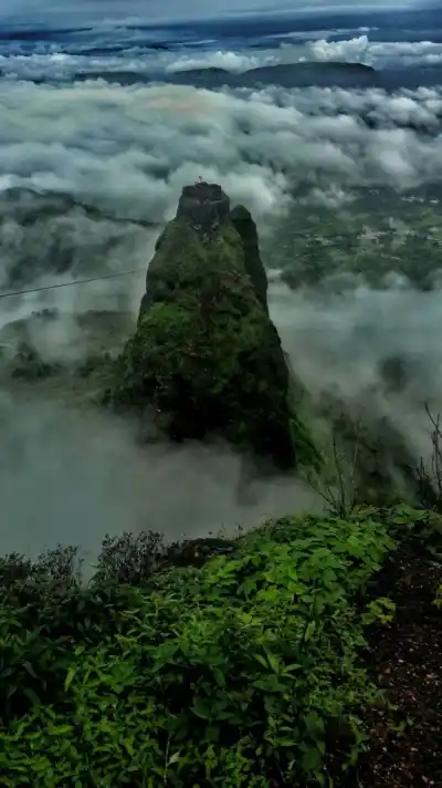 Spectacular view of green pinnacle rising out of clouds on Kalsubai Trek