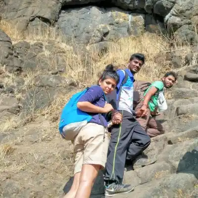 Tour Group climbing steep rock steps on cliff face on Rajgad to Torana Trek